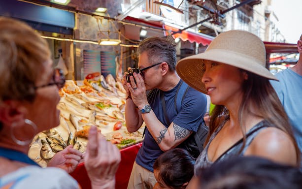 Tourists exploring a fish market during a cooking class in Palermo.