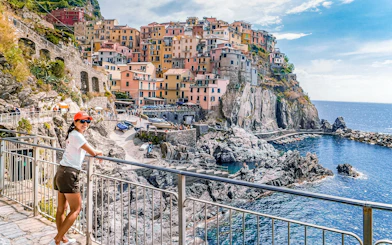 Woman enjoying the view of colorful cliffside buildings in Manarola, Cinque Terre, Italy.