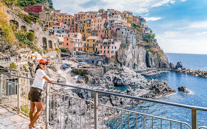 Woman enjoying the view of colorful cliffside buildings in Manarola, Cinque Terre, Italy.