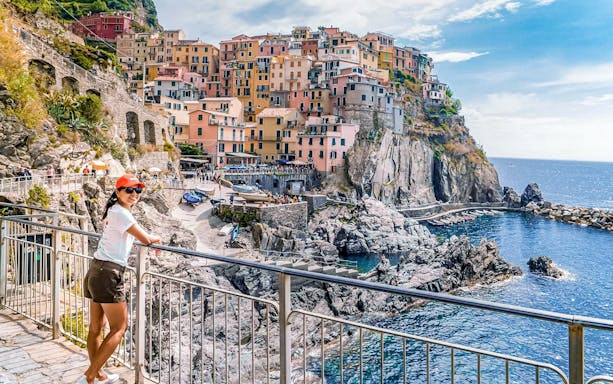Woman enjoying the view of colorful cliffside buildings in Manarola, Cinque Terre, Italy.