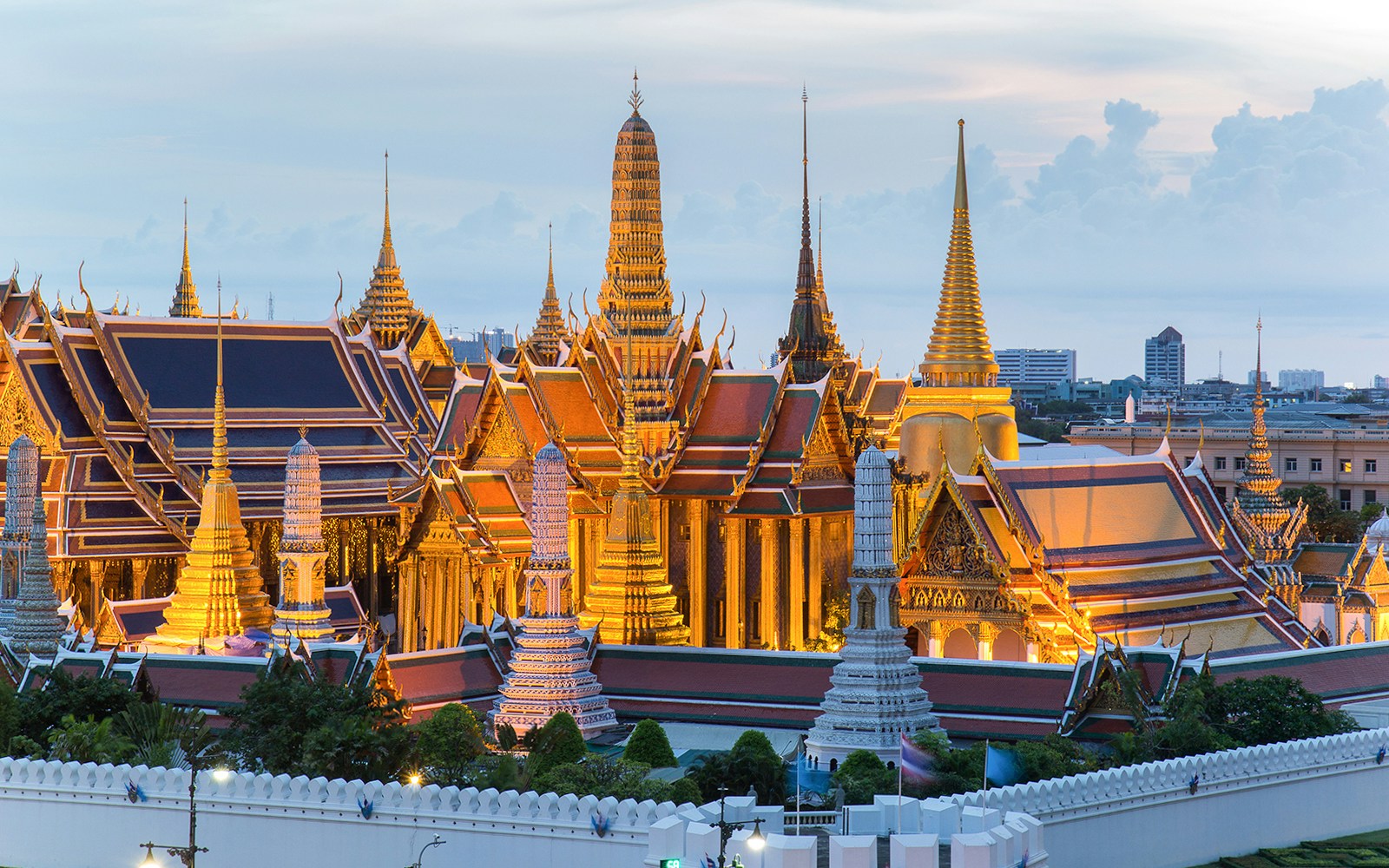 Grand Palace in Bangkok at dusk, featuring ornate spires and traditional Thai architecture.