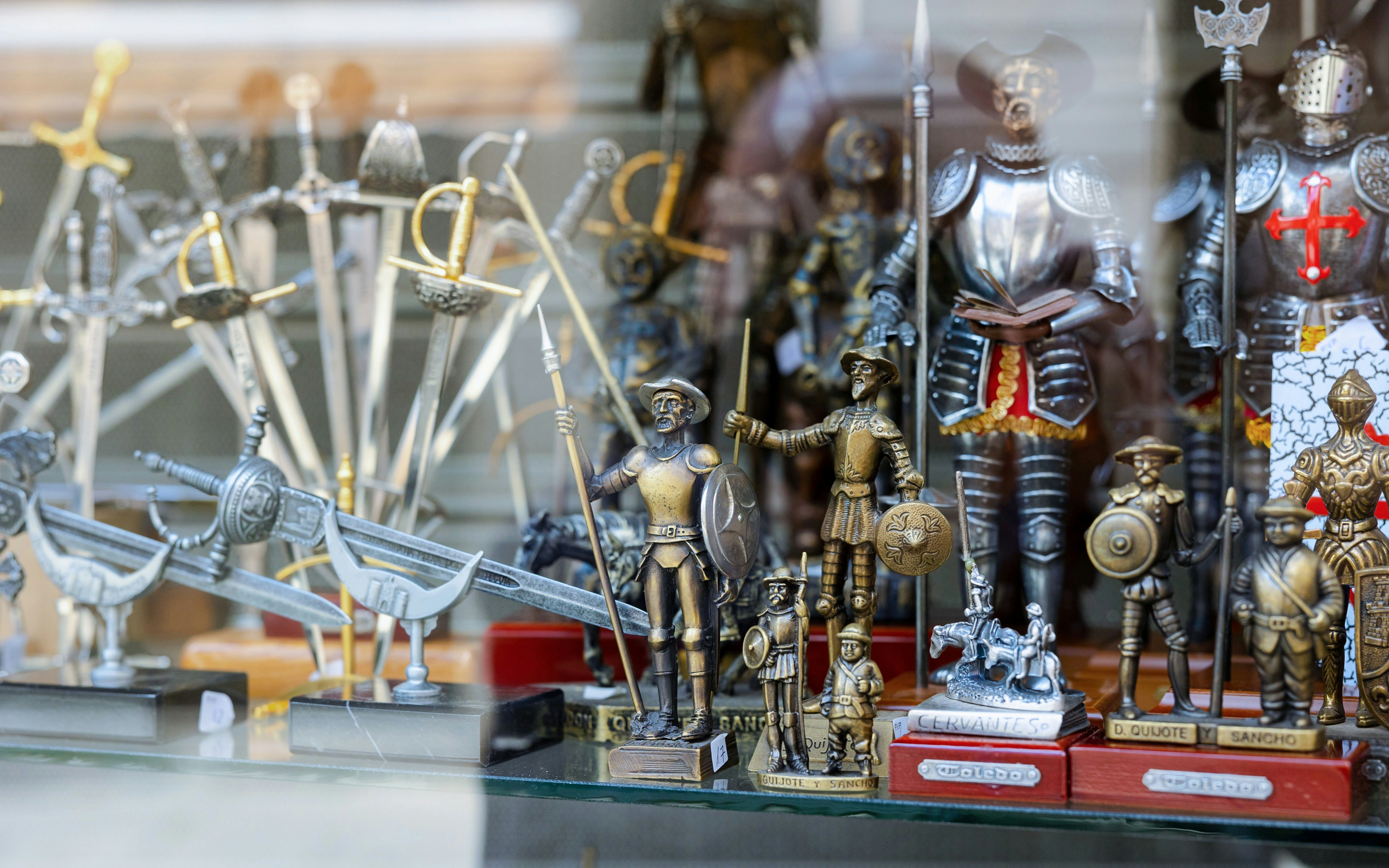Collection of Don Quixote figurines with swords and shields in a showcase.