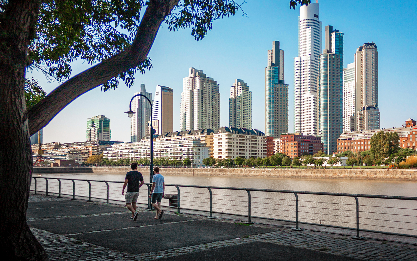 Buenos Aires river walk with people strolling and city skyline in the background.
