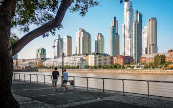 Buenos Aires river walk with people strolling and city skyline in the background.