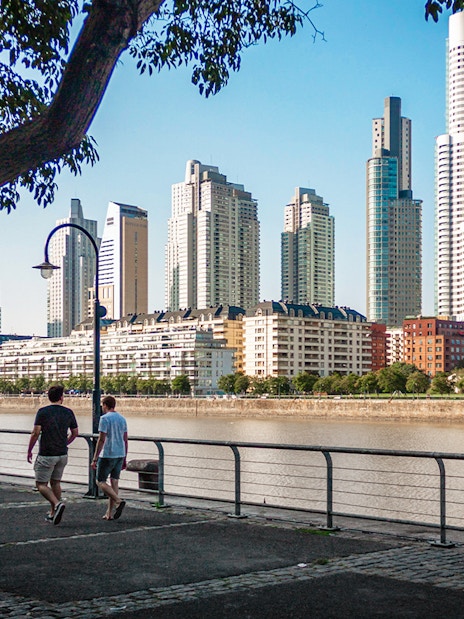 Buenos Aires river walk with people strolling and city skyline in the background.