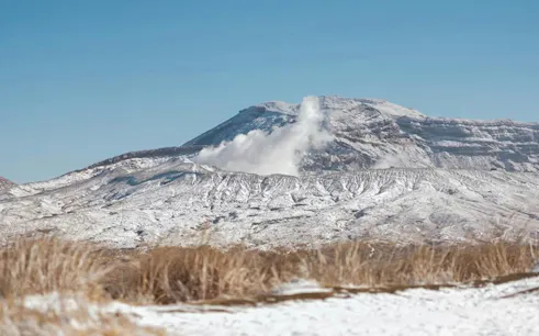 Snow-covered Mt Aso with steam rising, seen from Kusasenri Plain, Fukuoka day trip.