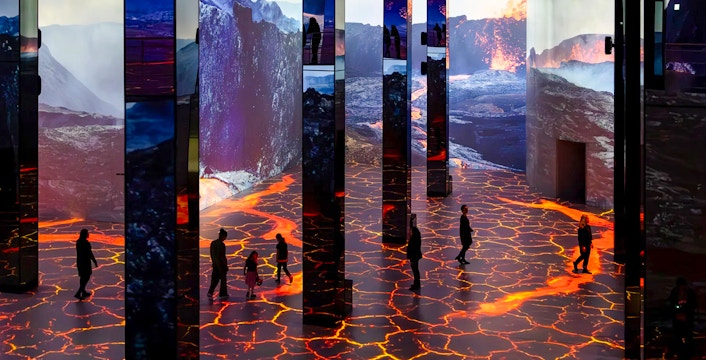 Guests exploring immersive Dinosaurs exhibition at Phoenix des Lumières Dortmund with volcanic visuals.