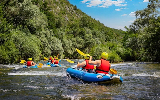 Rafting group navigating river near Split, surrounded by lush greenery.
