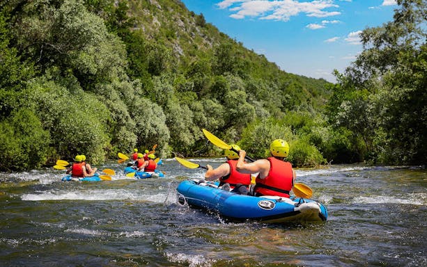 Rafting group navigating river near Split, surrounded by lush greenery.