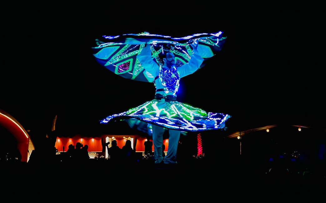 Dancer performing illuminated show during Abu Dhabi desert safari.