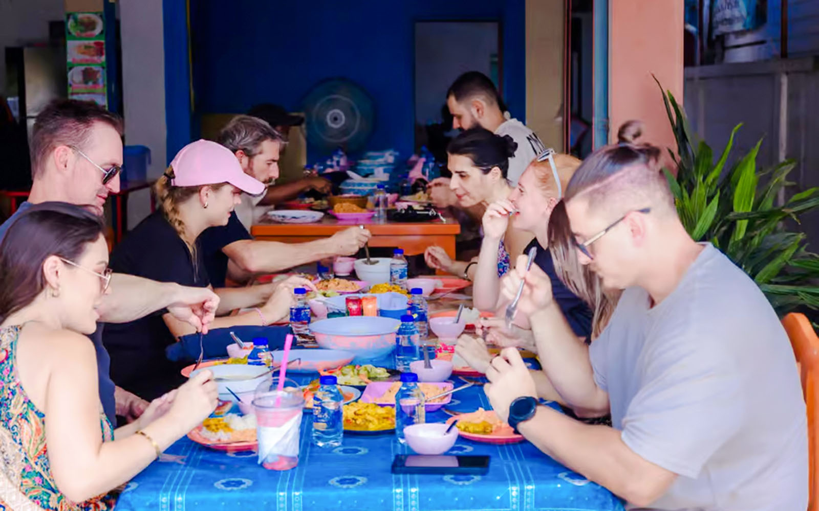 Tourists dining at a Thai buffet, enjoying various dishes at a communal table.
