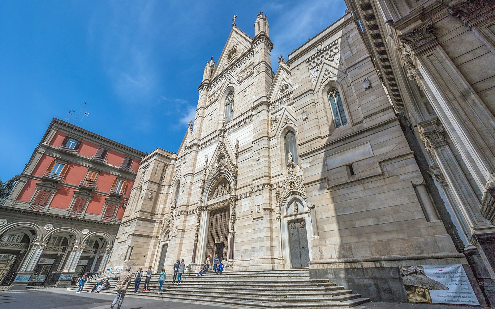 Naples Cathedral facade with visitors on steps, Italy.