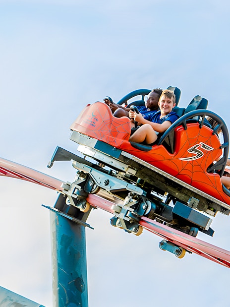 Roller coaster ride Tarantula at Parque de Atracciones de Madrid with smiling riders.