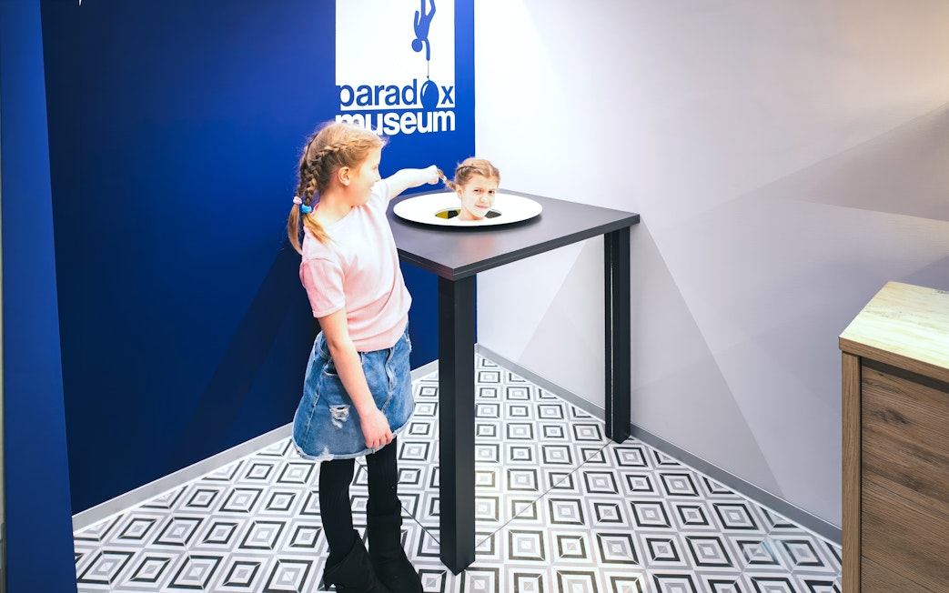 Girl interacting with optical illusion exhibit at Paradox Museum Stockholm.