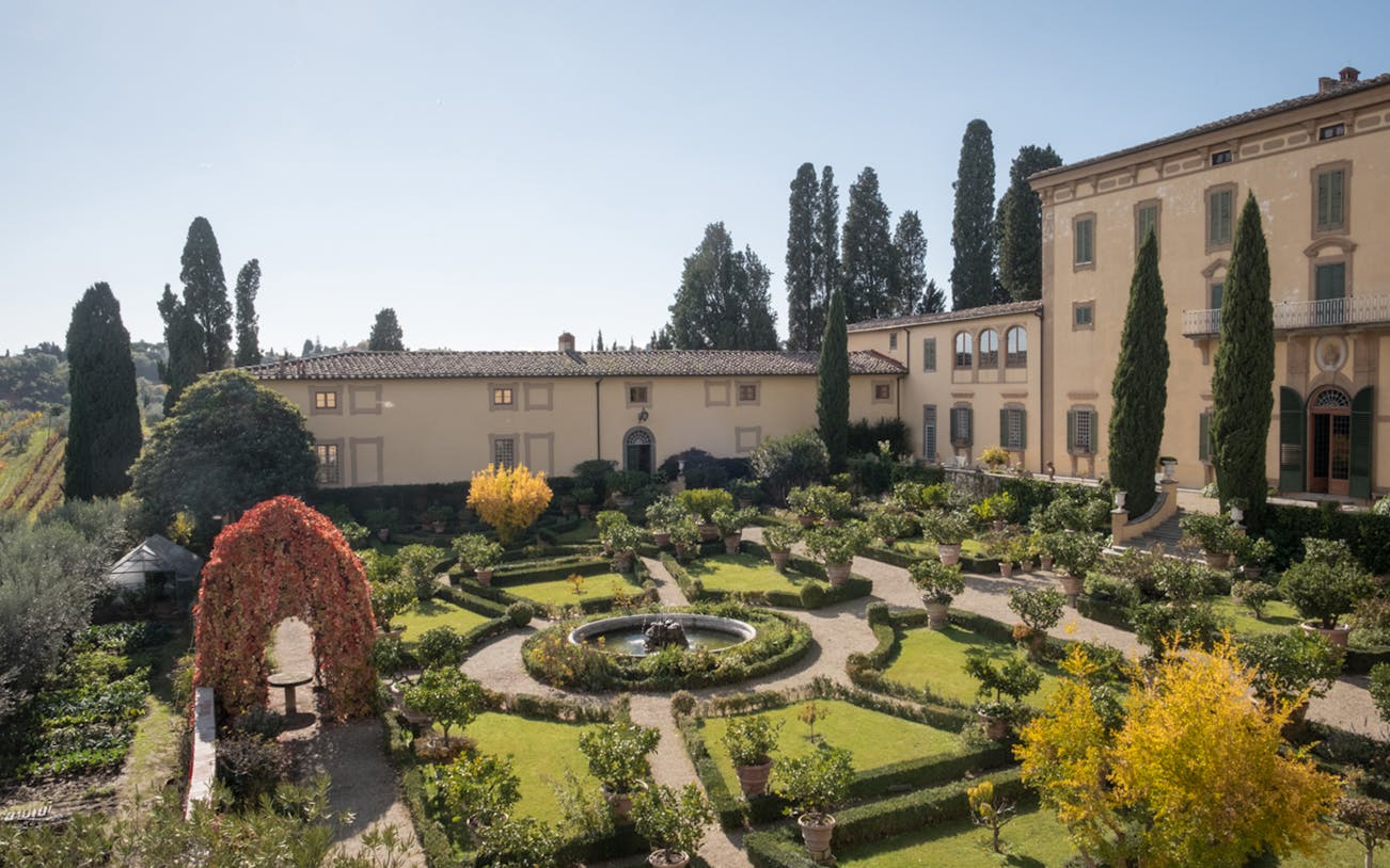 Elegant villa garden in Chianti with manicured hedges and fountain, part of wine tour from Florence.