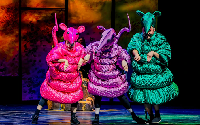 Performers in colorful animal costumes on stage during The Dragon Child in Sydney.