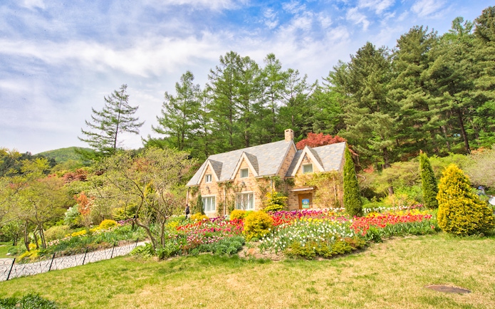 Stone cottage with tulip gardens and trees near Gapyeong, South Korea.