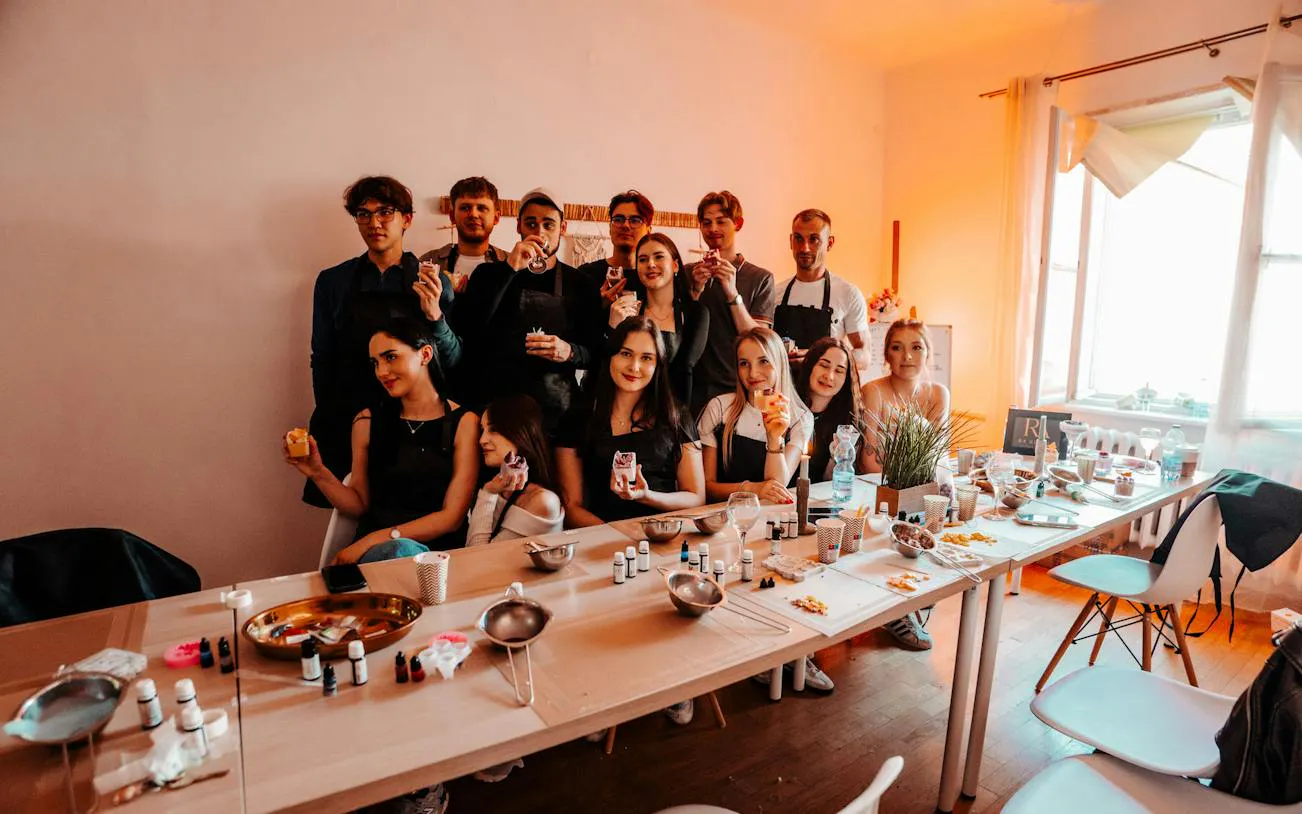 Group enjoying candle-making workshop in Krakow studio with fragrances, wine, and music.