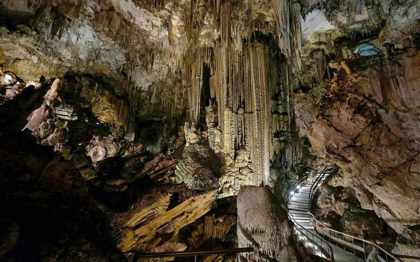 Stalactites and stalagmites in the Caves of Nerja, Spain, with a lit pathway.