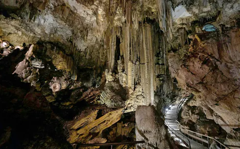 Stalactites and stalagmites in the Caves of Nerja, Spain, with a lit pathway.