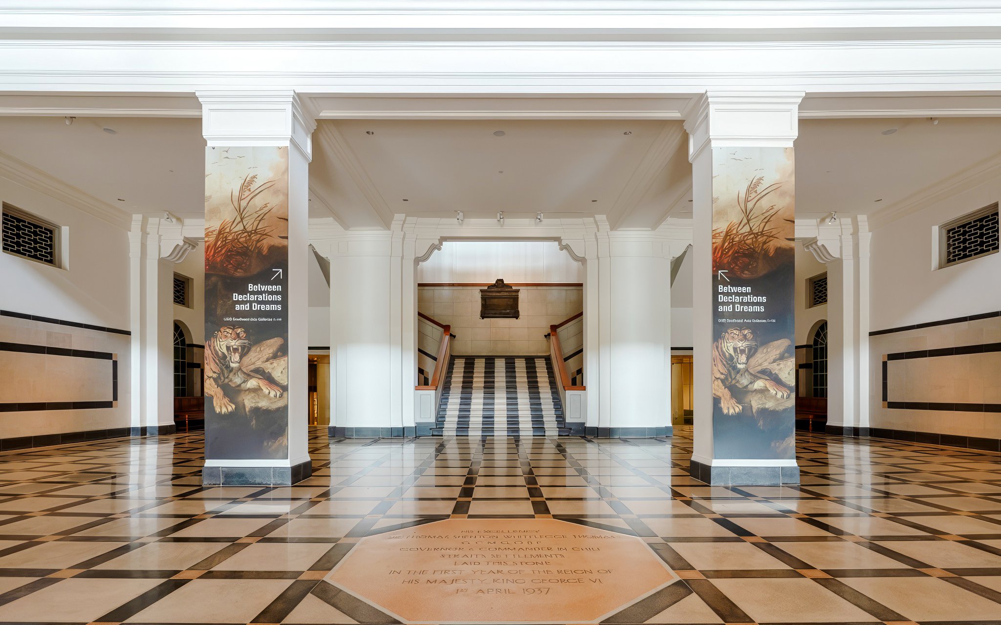 Hallway with columns and "Between Declarations and Dreams" banners, National Gallery Singapore.