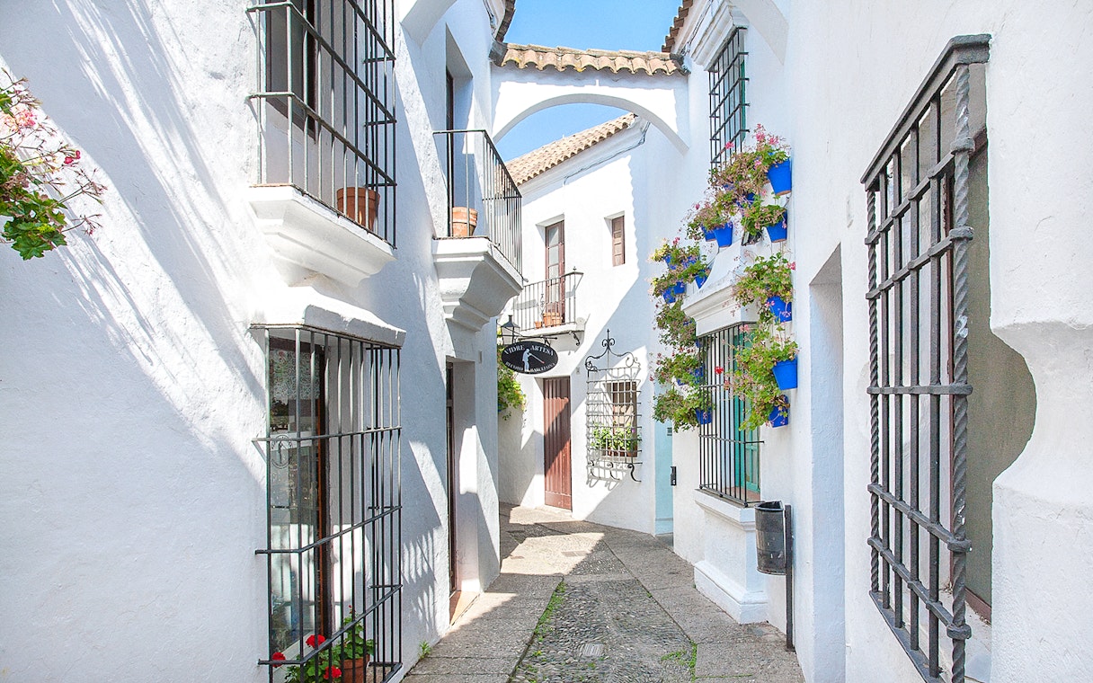 Narrow street with white buildings and flower pots in Poble Espanyol, Barcelona.