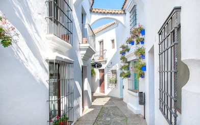 Narrow street with white buildings and flower pots in Poble Espanyol, Barcelona.