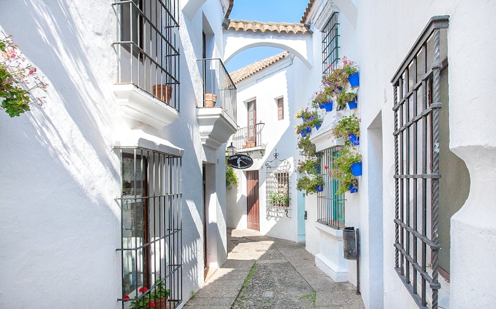 Narrow street with white buildings and flower pots in Poble Espanyol, Barcelona.