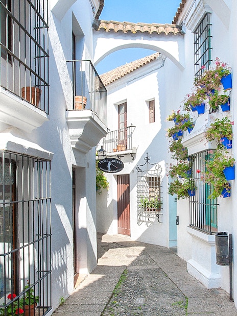 Narrow street with white buildings and flower pots in Poble Espanyol, Barcelona.