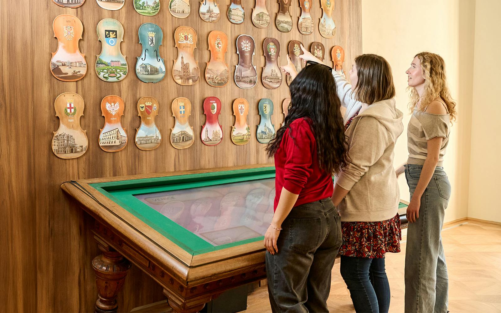 Visitors engaging with interactive violin displays at Prague Mozart Interactive Museum.