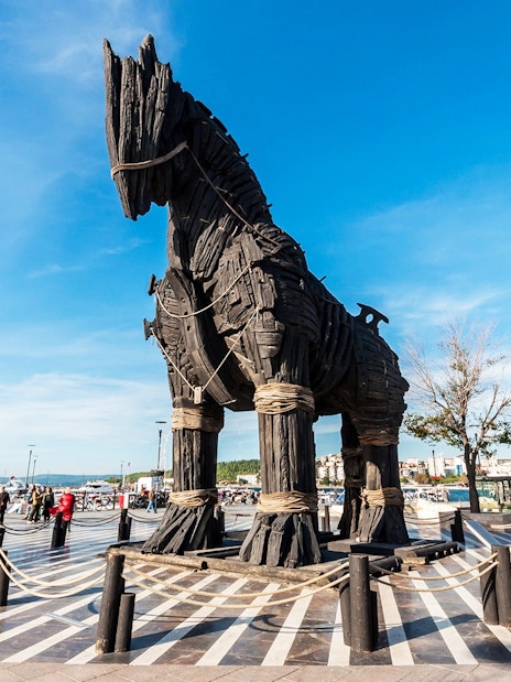 Trojan Horse replica at Troy archaeological site, Turkey, with visitors exploring.