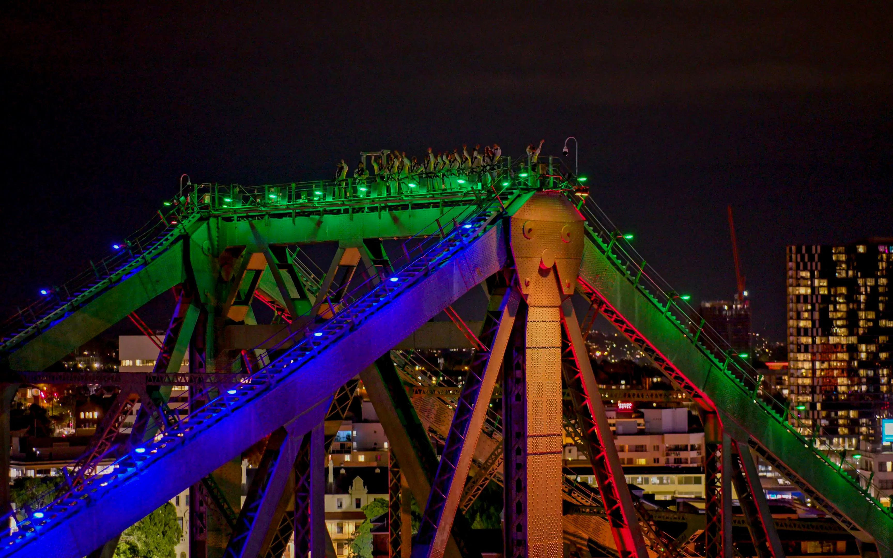 Climbers on illuminated Story Bridge at night in Brisbane, Australia.