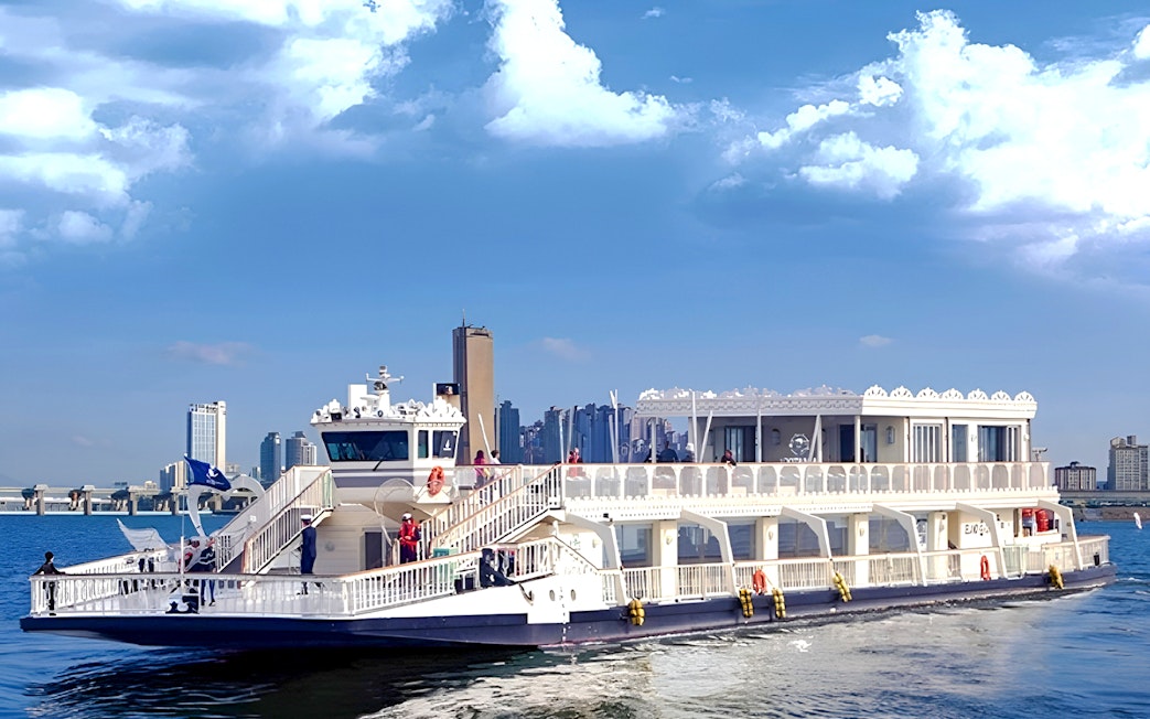 Cruise ship on Hangang River with Seoul skyline in the background.