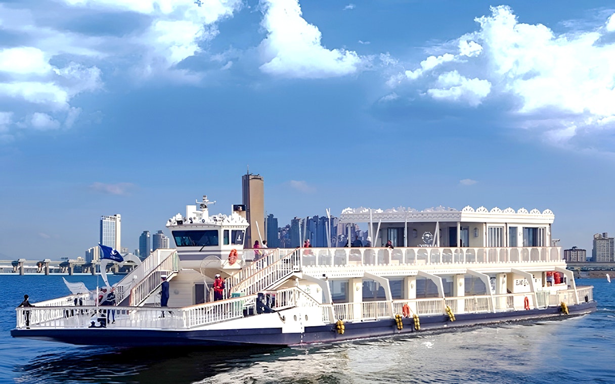 Cruise ship on Hangang River with Seoul skyline in the background.
