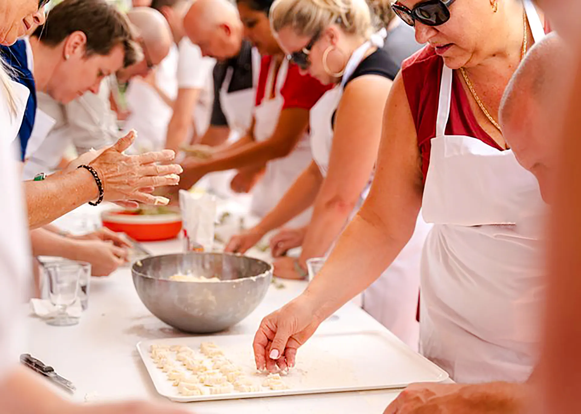 Participants in a Genoese cooking lesson in Genoa, making pasta at a table.