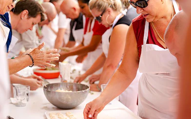 Participants in a Genoese cooking lesson in Genoa, making pasta at a table.