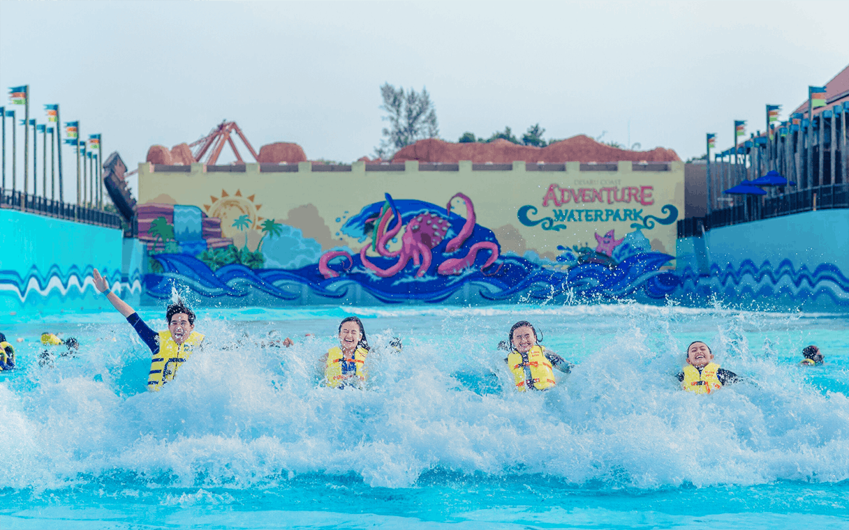 Tourists in life jackets enjoying wave pool at Adventure Waterpark Desaru Coast.