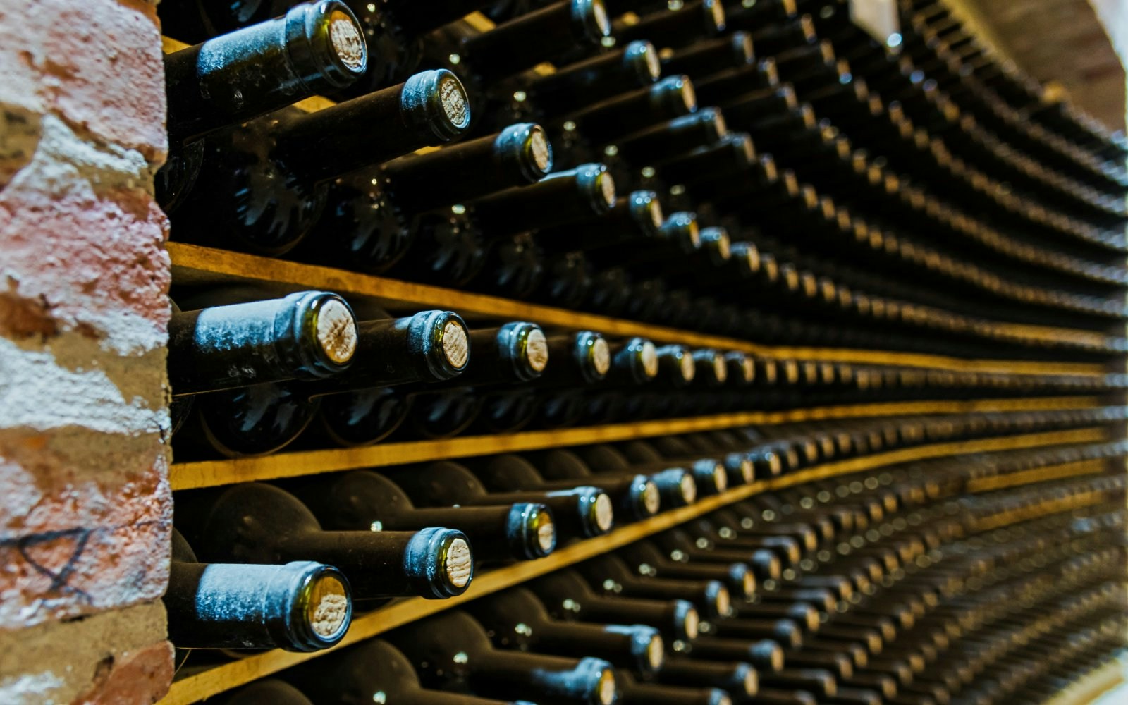 Red wine bottles stacked in a winery cellar.