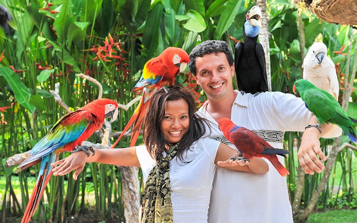 Couple with colorful parrots at Madrid Zoo Aquarium.