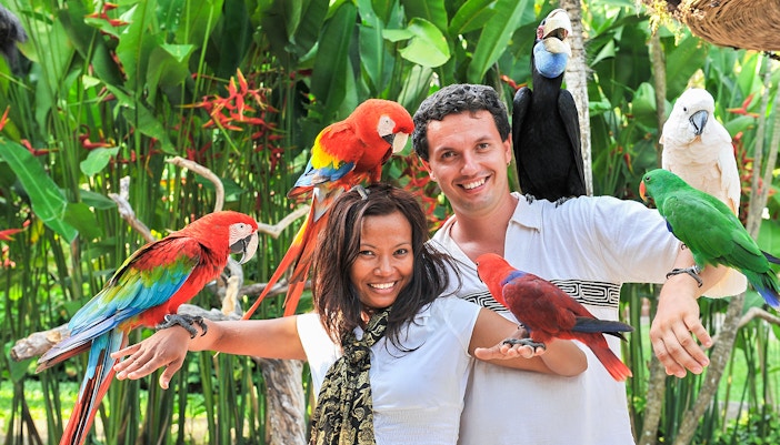 Couple holding colorful parrots at Madrid Zoo Aquarium.