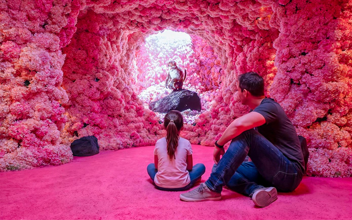 Visitors observing a monkey sculpture inside a pink floral cave at Mercer Labs Museum of Art.