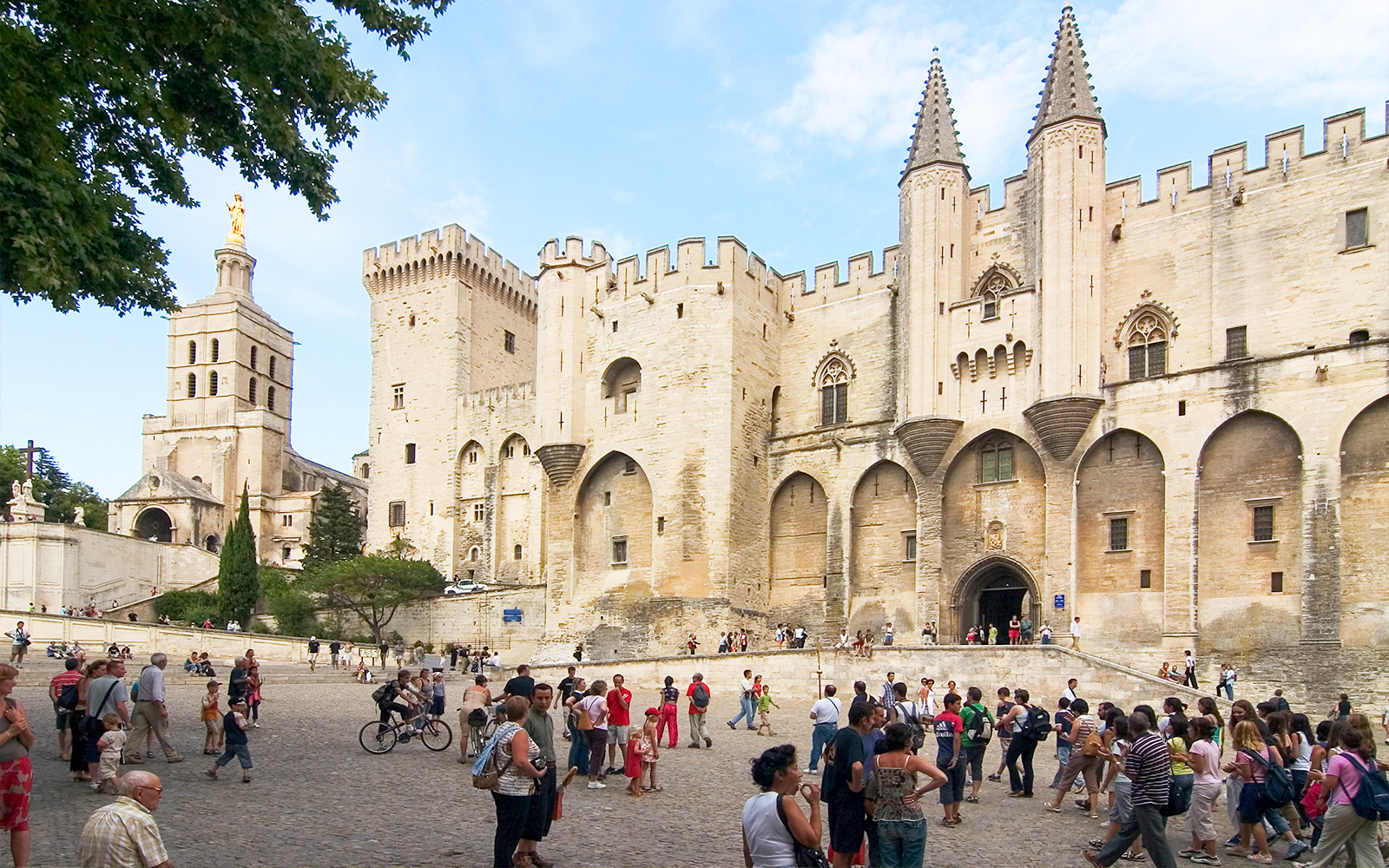 Palace of the Popes in Avignon with tourists exploring the historic site.