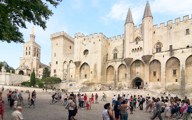 Palace of the Popes in Avignon with tourists exploring the historic site.