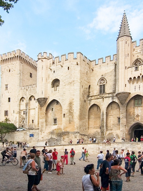 Palace of the Popes in Avignon with tourists exploring the historic site.