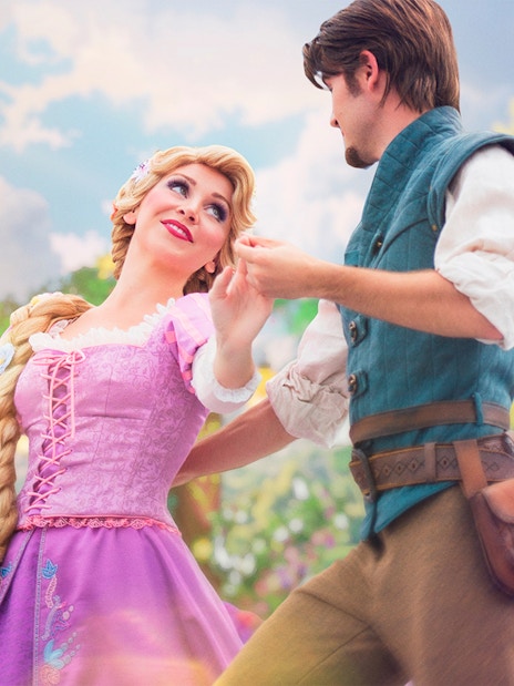 Rapunzel and Flynn dancing at Disneyland Paris with lanterns and floral backdrop.