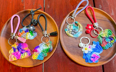Colorful elephant keychains on wooden plates at Krabi Elephant Local Project workshop.