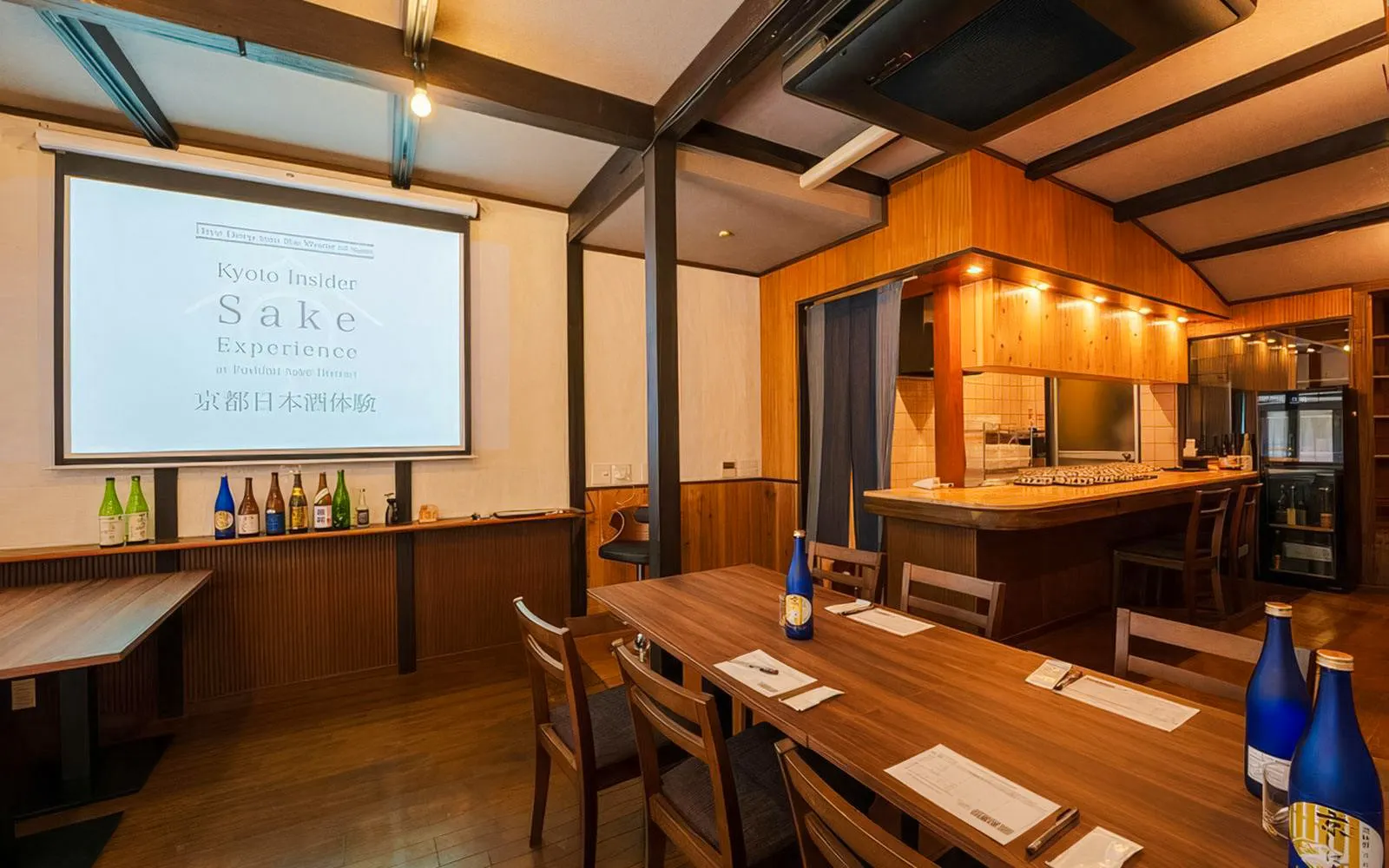 Interior seating area with tables and sake bottles at Kyoto Insider Sake Experience.