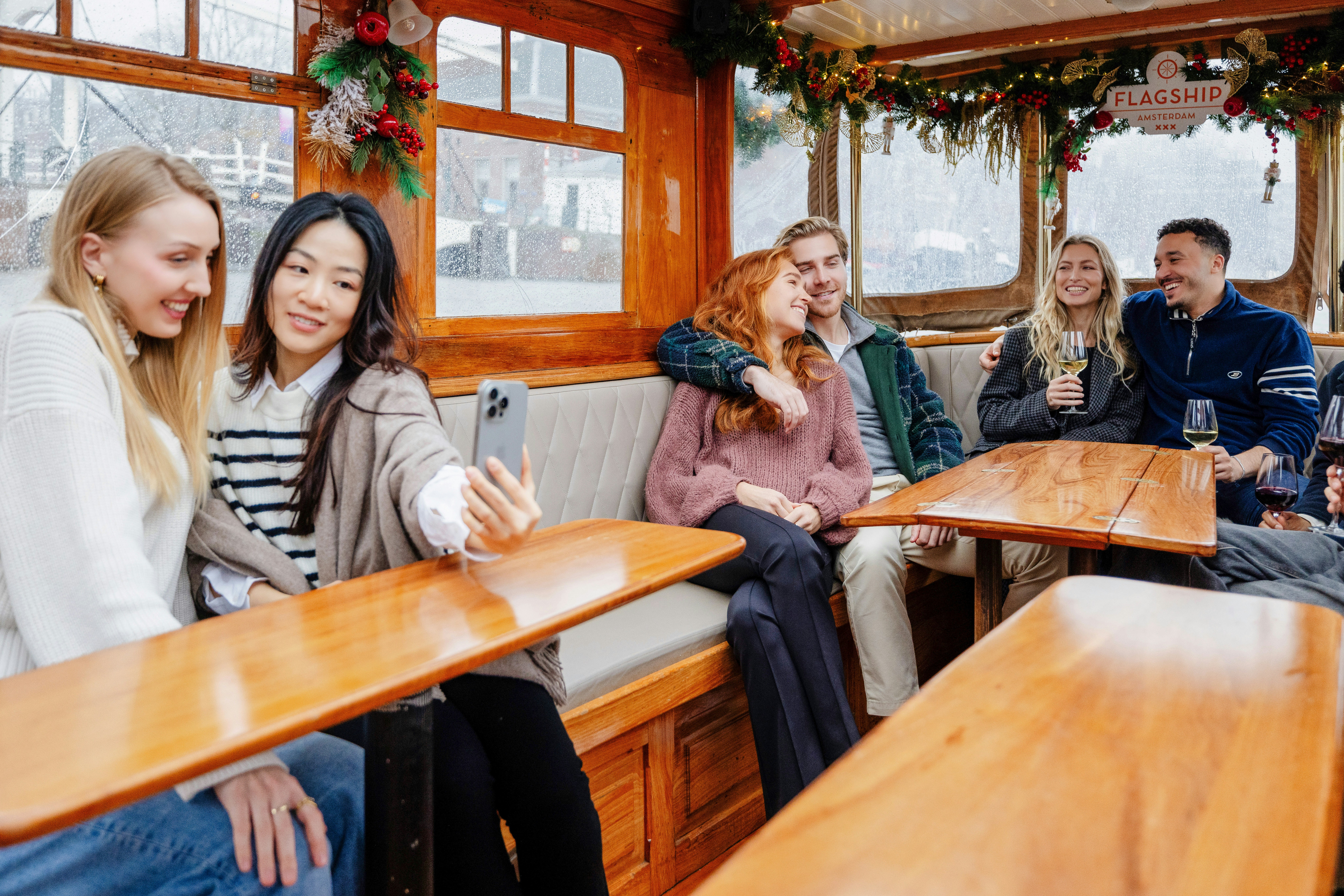 Guests enjoying an evening canal cruise in Amsterdam, passing illuminated bridges and historic buildings in winter.