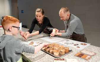 Chocolate workshop in Brussels with participants piping chocolate designs.