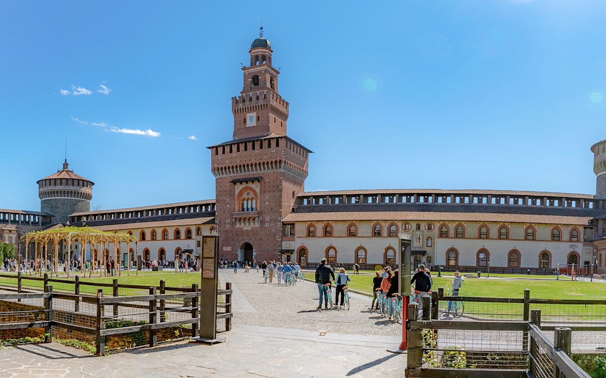 Courtyard of Sforza Castle in Milan with tourists and historic architecture.